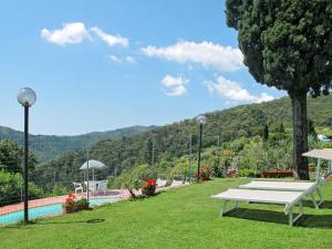a white bench sitting in the grass near a swimming pool at Holiday Home Sara by Interhome in Gello