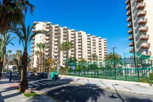 ein großes Apartmenthaus mit Palmen und einer Straße in der Unterkunft Apartamento Las Góndolas Playa ALOJAMIENTOS VISTAMAR in Almuñécar