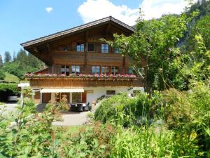 une maison dans les montagnes avec des fleurs sur le balcon dans l'établissement Apartment Giferblick by Interhome, à Zweisimmen