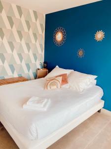 um quarto com uma cama branca e uma parede azul em Le Clos Vernay em Nivolas-Vermelle