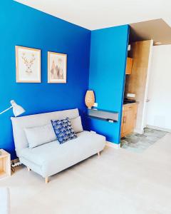 a living room with a white couch and blue wall at Le Clos Vernay in Nivolas-Vermelle
