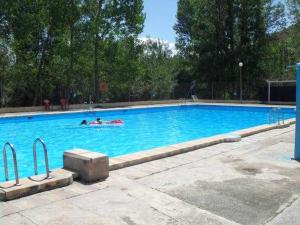 two people swimming in a large blue swimming pool at Casa Rural Casa Antiga in Los Santos