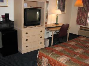 a hotel room with a bed and a desk with a television at Canterbury Inn & Suites in Parsons