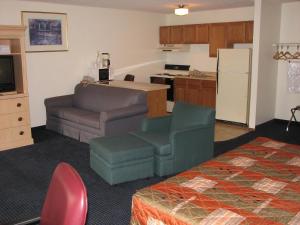 a living room with a couch and a kitchen at Canterbury Inn & Suites in Parsons