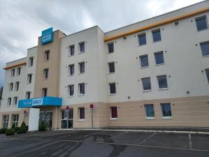 a large white building with a parking lot at Kyriad Direct Arras - Saint-Laurent-Blangy - Parc Expo in Saint-Laurent-Blangy