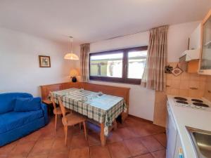 cocina y comedor con mesa y sofá azul en Apartment Roacia by Interhome, en Alba di Canazei