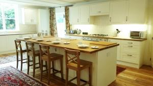 a kitchen with a large wooden island with bar stools at East End House in Bury Saint Edmunds