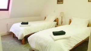 two beds in a room with white sheets and green towels at East End House in Bury Saint Edmunds