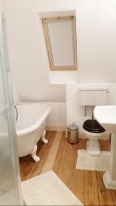 a bathroom with a tub and a toilet and a sink at East End House in Bury Saint Edmunds