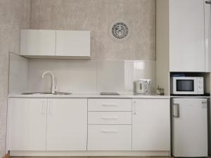 a kitchen with white cabinets and a microwave and a refrigerator at Comfort in Chernihiv +12 photos