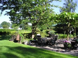 um jardim com uma mesa e cadeiras debaixo de uma árvore em 't Rond Bargie em Exloo