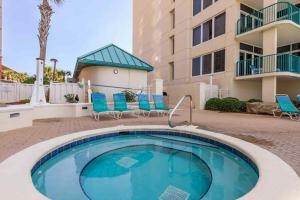 a swimming pool with blue chairs and a building at Jade East Towers 720 in Destin
