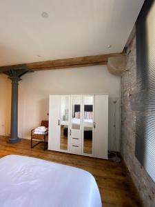 プリマスにあるBuckingham Place at the Royal William Yardの白いベッドとレンガの壁が備わるベッドルーム1室が備わります。
