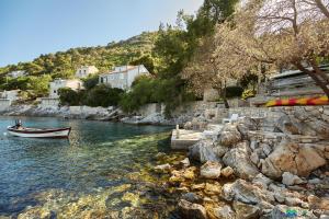 a boat in the water next to some rocks at Mljet 4 You - seafront apartment in Sobra