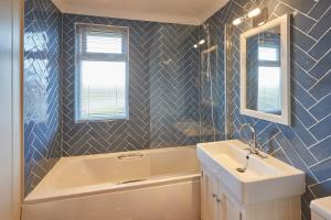 ein Badezimmer mit einer Badewanne, einem Waschbecken und einem Spiegel in der Unterkunft Host & Stay - Salt & Seaweed in Runswick