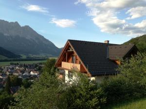 dom na wzgórzu z górami w tle w obiekcie Grimming Appartement Schladming w mieście Sonnberg