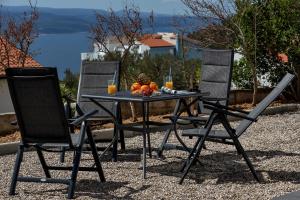 einen Tisch mit einer Obstschale und 2 Stühlen in der Unterkunft Holiday home L & B Makarska in Makarska