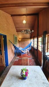 a room with a table and a hammock in a house at Pousada Terra da Luz in Visconde De Maua