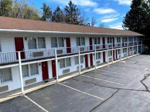 a white building with red doors and a parking lot at Economy Lodge 682 Main St Sturbridge in Sturbridge
