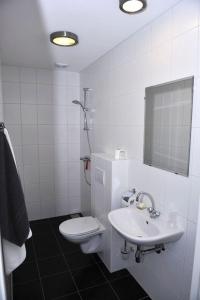 Baño blanco con aseo y lavamanos en Hotel Royal, en IJmuiden