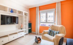 a living room with an orange wall at Piso de diseño junto al centro de Murcia con parking in Murcia