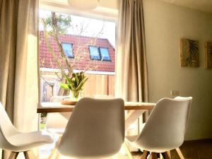 a dining room with a table and chairs and a window at Bendalong Noordwijk in Noordwijk