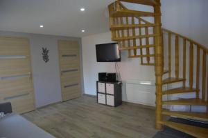 a living room with a wooden staircase and a television at Jolie maison de centre-ville: Le Tournesac in Héricourt