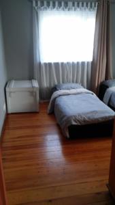 a bedroom with a bed and a window and a wooden floor at Pokoje na Pogodnie in Szczecin