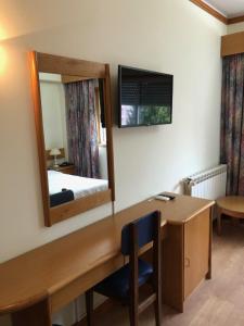 Zimmer mit einem Schreibtisch, einem Spiegel und einem Bett in der Unterkunft HOTEL CRUZ DA MATA in Mangualde