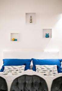 1 cama con almohadas azules en una habitación blanca en Dimora Jolanda, en Conversano