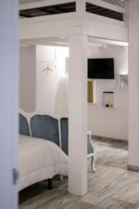 een witte slaapkamer met een bed en een televisie bij Dimora Jolanda in Conversano