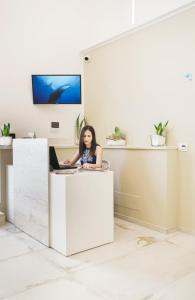 a woman sitting at a desk with a laptop at Oasi del Golfo Suites B&B in Castellammare del Golfo