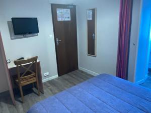 a bedroom with a bed and a desk and a television at Hotel & Restaurant Hanoï Station in Saint Malo