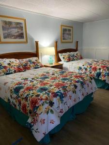 a hotel room with two beds with floral sheets at The Palms Motel in Geneva-on-the-Lake