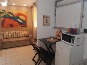 sala de estar con microondas y mesa en Charmoso Loft Studio para temporada - Recreio - Barra - RJ, en Río de Janeiro