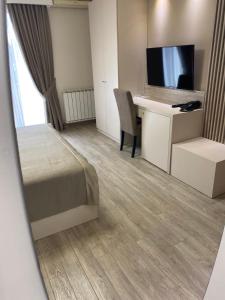 Habitación de hotel con cama y escritorio con TV. en Hotel Holiday, en Podgorica