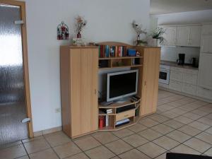 a television in a wooden entertainment center in a kitchen at Detached holiday home with fenced garden in Schmiedefeld am Rennsteig