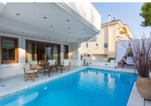 a house with a swimming pool with a table and chairs at Villa Ariadne in Athens