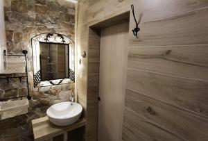 a bathroom with a white sink and a stone wall at Studio Apartman Lipik in Lipik