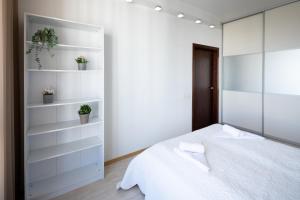 sypialnia z białym łóżkiem i białymi półkami w obiekcie Riga Riverside One Bedroom Apartment w Rydze