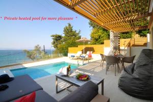 MpoukarisCasa del Mar的带游泳池、桌椅的露台