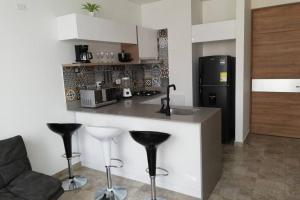 a kitchen with a counter with stools and a refrigerator at Apartamento en edificio full, Rodadero Santa Marta in Gaira