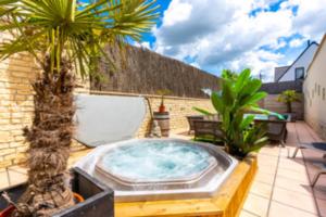 un bain à remous sur une terrasse avec des palmiers dans l'établissement Vlaamse Ardennen Vakantiehuis Casa Caliente met wellness, à Avelgem