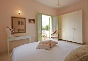 Schlafzimmer mit einem weißen Bett, einem Spiegel und einem Fenster in der Unterkunft Flower and Crafts - The Eco Nature House in Monolithos