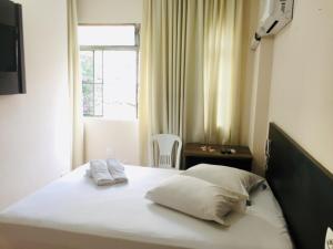 a bedroom with a bed with two pillows and a window at Hotel GMatos Belo Horizonte - Próximo a Rodoviária e Mercados Turísticos in Belo Horizonte
