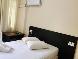 a bedroom with a bed with white sheets and pillows at Hotel GMatos Belo Horizonte - Próximo a Rodoviária e Mercados Turísticos in Belo Horizonte