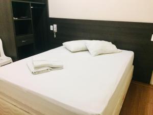 a white bed with two towels on top of it at Hotel GMatos Belo Horizonte - Próximo a Rodoviária e Mercados Turísticos in Belo Horizonte