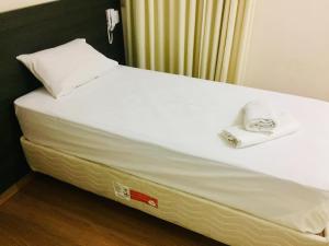 a bed with a white mattress and a phone on it at Hotel GMatos Belo Horizonte - Próximo a Rodoviária e Mercados Turísticos in Belo Horizonte