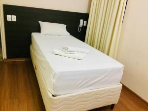 a bed with two white slippers on top of it at Hotel GMatos Belo Horizonte - Próximo a Rodoviária e Mercados Turísticos in Belo Horizonte