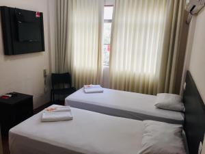 two beds in a hotel room with a television at Hotel GMatos Belo Horizonte - Próximo a Rodoviária e Mercados Turísticos in Belo Horizonte